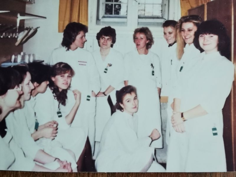eine Gruppe von jungen Frauen stehen in der Umkleidekabine ihrer Akademie für Radiologie Technologinnen. sie tragen weiße Mäntel und weiße Hosen. 